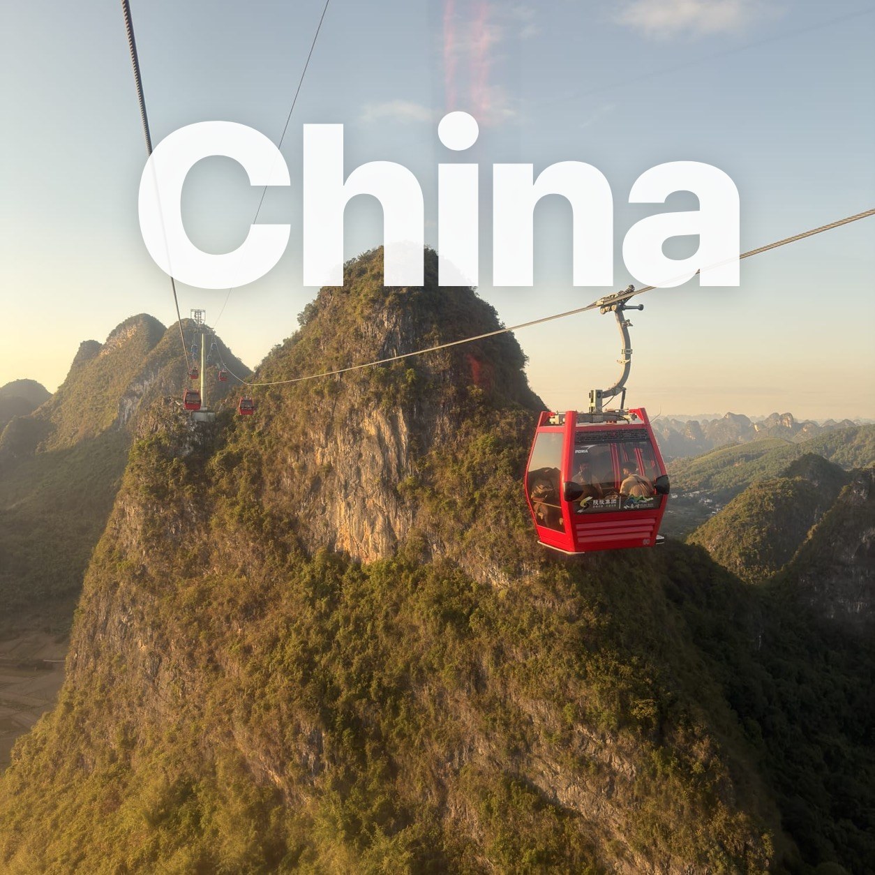 A red cable car floating between karst peaks at golden hour near Yangshuo.