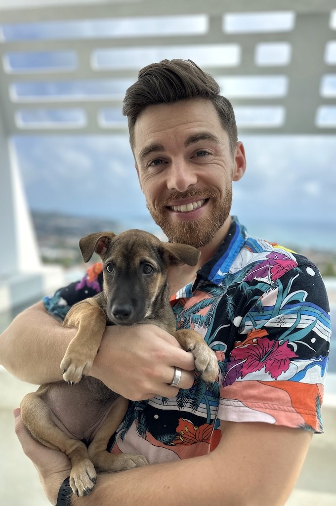 Paul holding a puppy while wearing a bright patterned shirt.